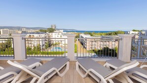 A balcony with sun loungers, a view of a pool, and surrounding buildings. - Rome Palace Deluxe (Sunny Beach)