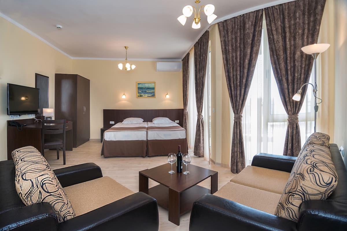 Una habitación de hotel con cama, escritorio, televisión, sofá y mesa de centro.