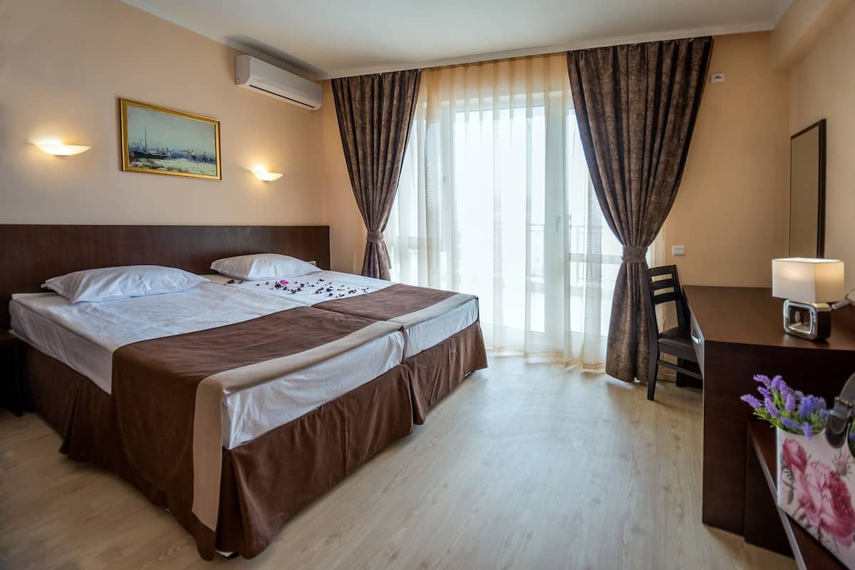 Habitación de hotel con cama doble, escritorio, silla, lámpara de escritorio y un cuadro en la pared.