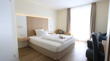 Una habitación de hotel moderna con una cama grande, un escritorio, una silla y una ventana con cortinas.