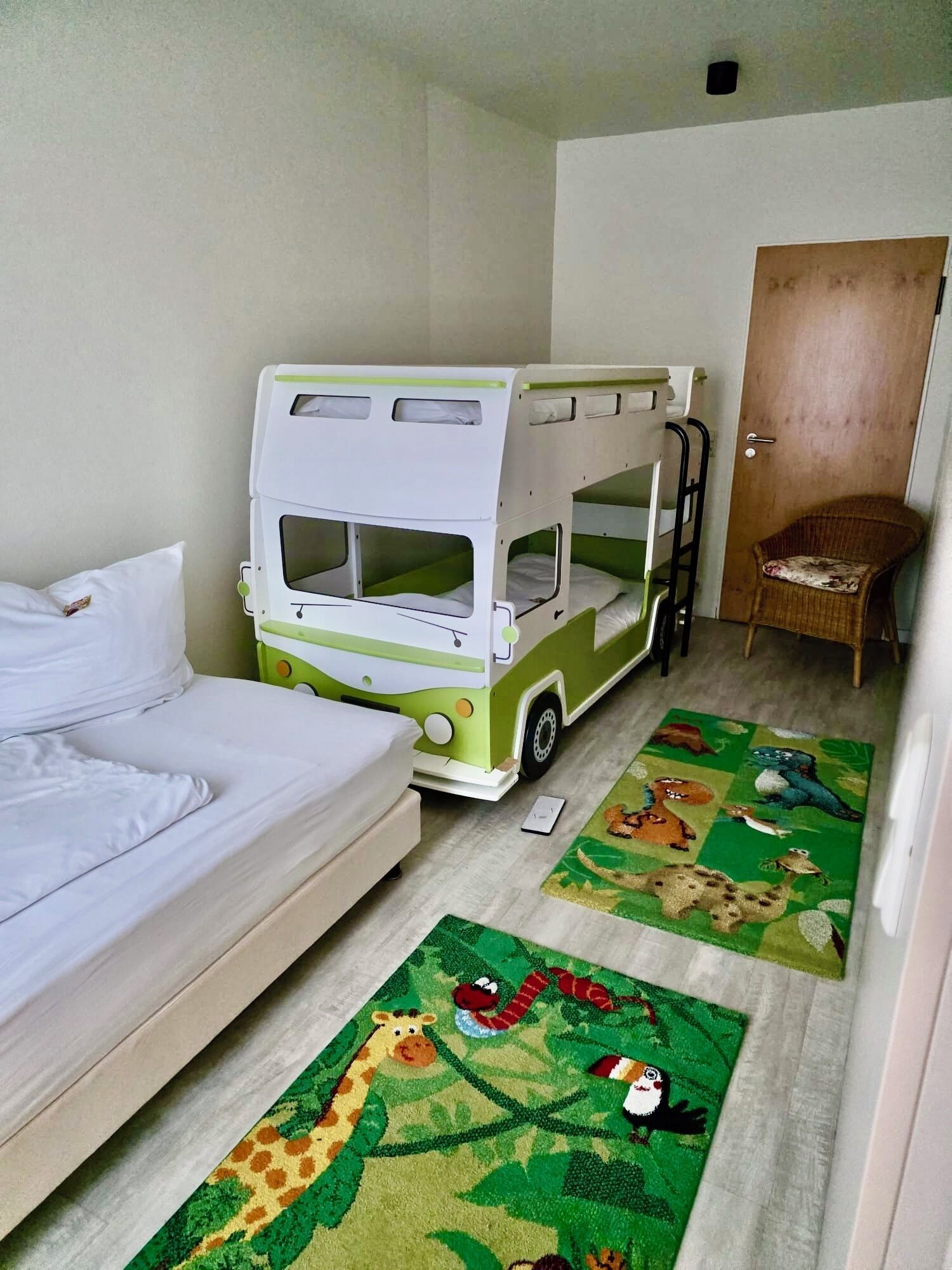 A room with a bunk bed, a single bed, a chair, and two rugs with animal designs.