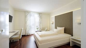 A modern hotel room with a large bed, a desk, and a chair.