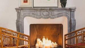 A fireplace with lit candles, a framed picture above it, and a statue to the right. - B&B San Clemente (Crema)