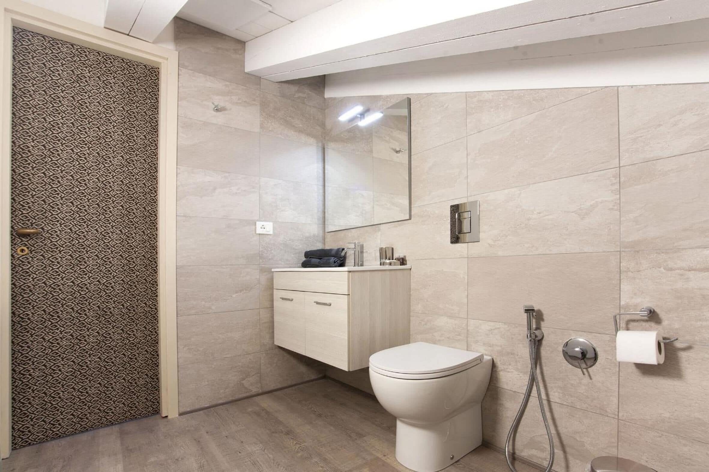 Une salle de bain moderne comprenant des toilettes, un meuble-lavabo avec des tiroirs, un miroir et un espace douche.