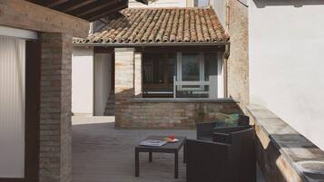 Un patio techado con tejas, un muro de ladrillo y una ventana que da al interior.