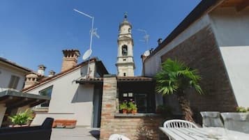 Ein Innenhof mit einem weißen Gebäude, das einen Glockenturm, eine Satellitenschüssel und einen kleinen Garten mit Blumentöpfen zeigt.