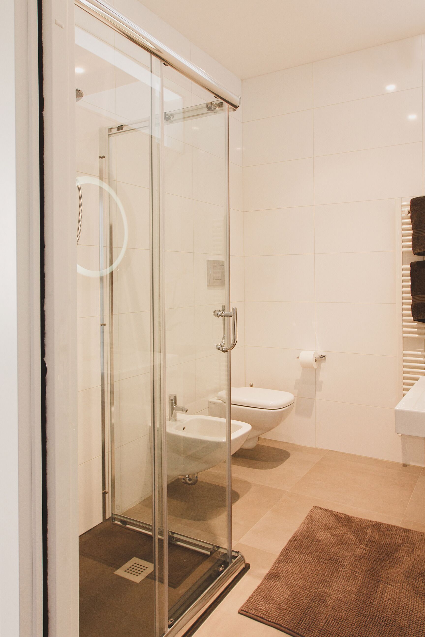 Un baño moderno con cabina de ducha de vidrio, inodoro y lavamanos.