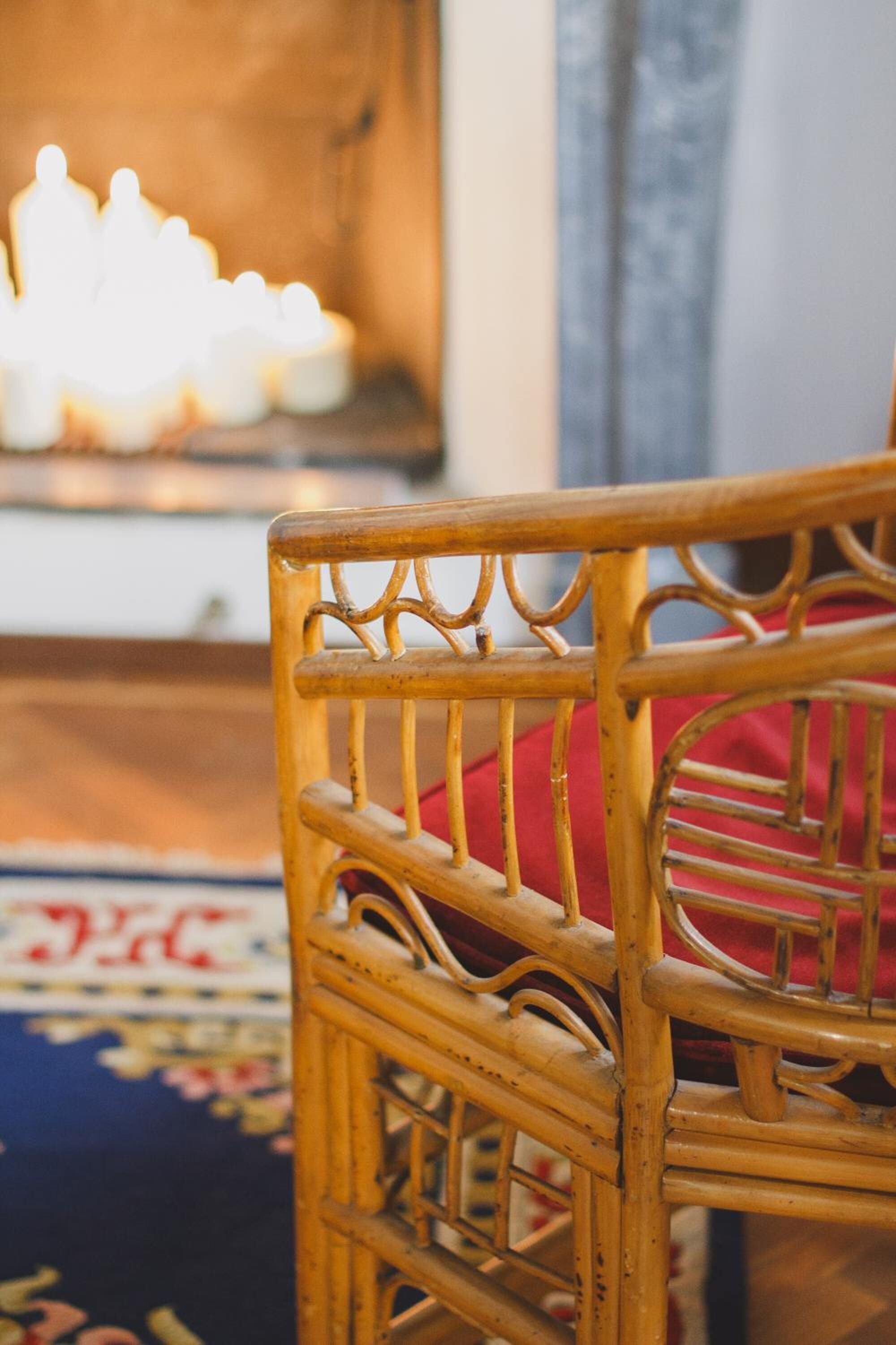 A wicker chair with a red cushion in a room with a patterned carpet.