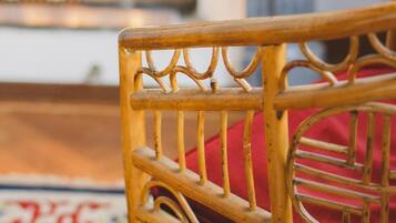 A wicker chair with a red cushion in a room with a patterned carpet.
