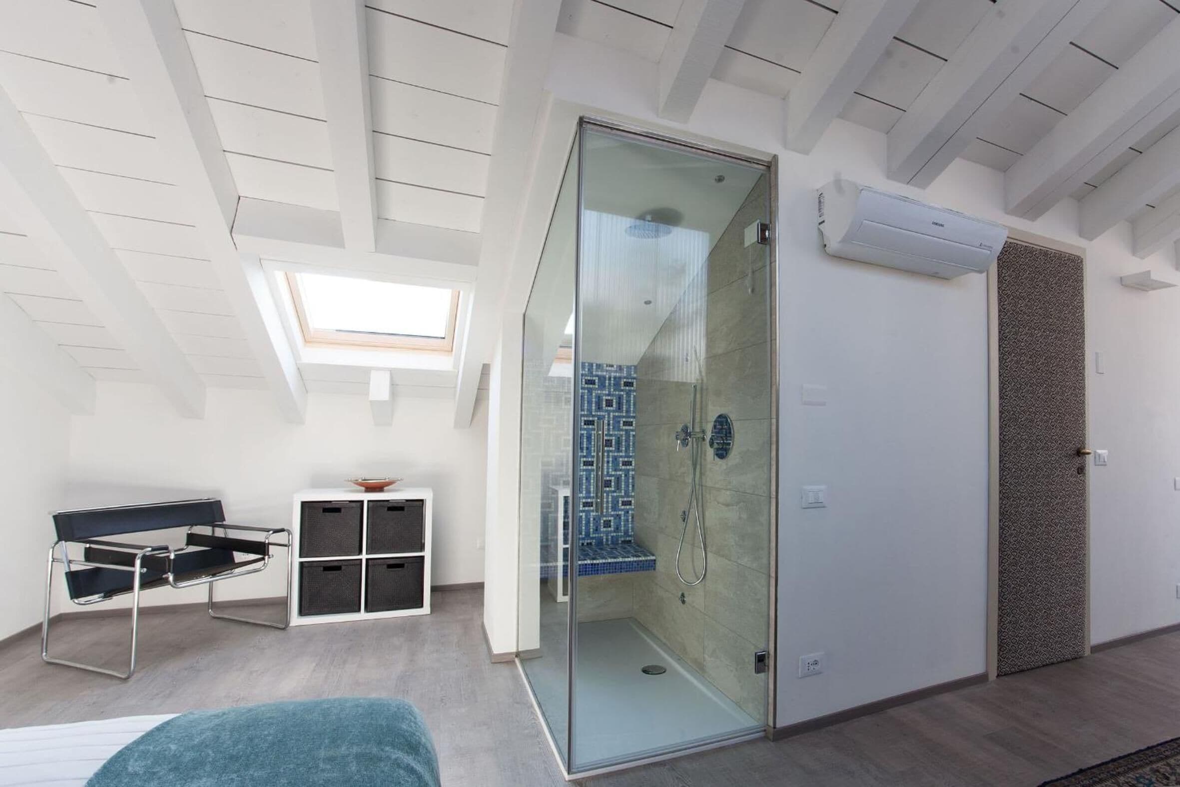 A modern bathroom with a glass shower enclosure, a built-in bench, and a skylight.