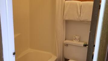 Un baño con bañera, inodoro y cortina de ducha.