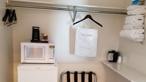 A compact laundry room with a white refrigerator, a microwave, and a drying rack. - Plaza Motel (Preston)