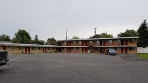A motel with multiple rooms, a parking lot, and a staircase leading to the upper floor. - Plaza Motel (Preston)