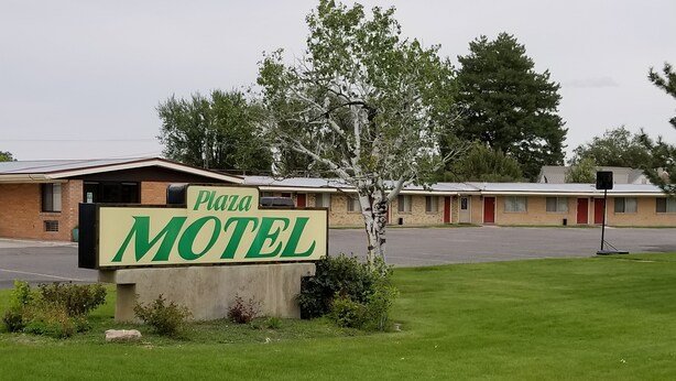 A motel sign with the name "Plaza Motel" and a parking lot in the background. - Plaza Motel (Preston)