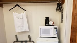 A compact laundry area with a washing machine, a microwave, and a drying rack. - Plaza Motel (Preston)