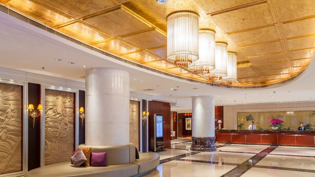 Eine großzügige Lobby mit einer Rezeption, hohen Säulen und einer Sitzecke.