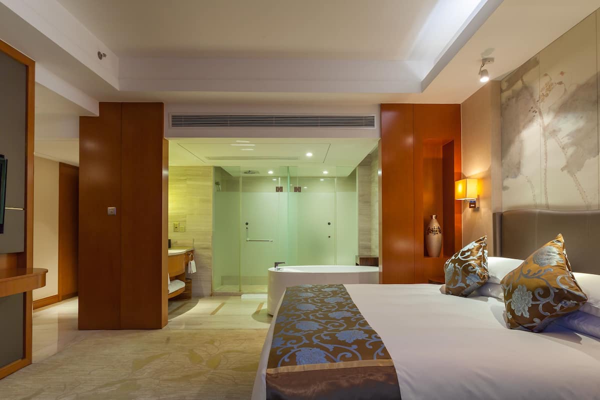 Ein Hotelzimmer mit einem großen Bett, einer Sitzecke, einer Dusche und einem Badezimmer.