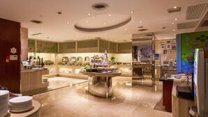 Eine moderne Hotelhalle mit einer zentralen Büfettinsel, einer Rezeption und einer Wand mit einer Uhr.