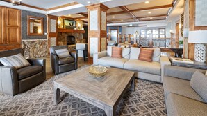 A spacious living area with a fireplace, leather sofas, a coffee table, and a patterned rug.