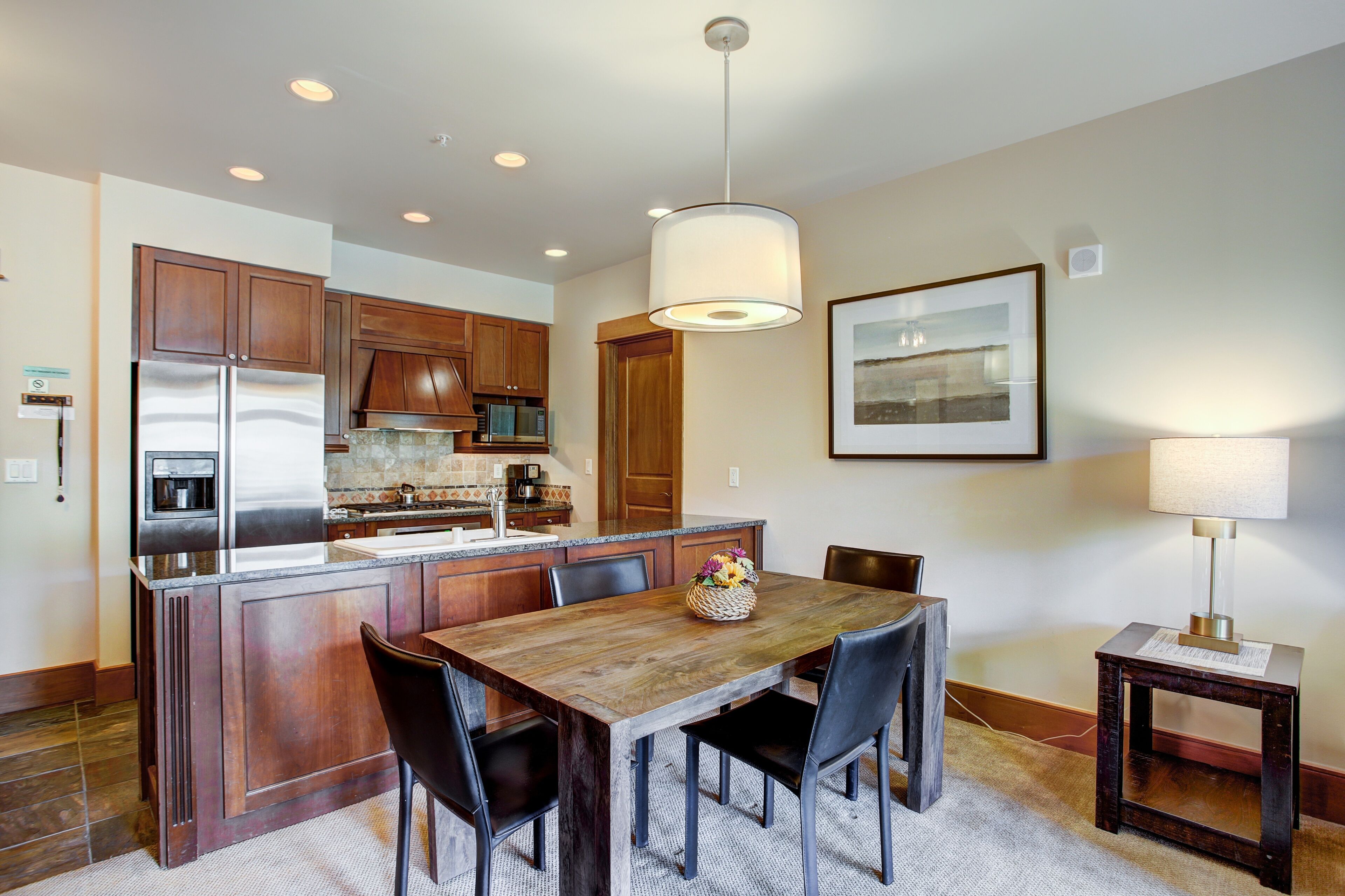 A modern kitchen with wooden cabinets, a stainless steel refrigerator, and a central island with seating.