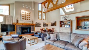 A spacious living room with a fireplace, leather sofas, a dining area, and a kitchen visible through an open archway. - Lenawee 1735 (Keystone)