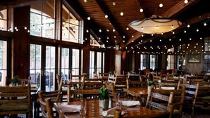A restaurant with wooden tables and chairs, large windows, and hanging lights. - Two Bedroom at the Lodge At Vail by RedAwning (Vail)