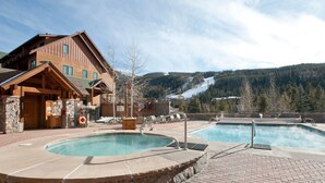 Un espace piscine avec un chalet en bois et une vue sur une montagne enneigée.