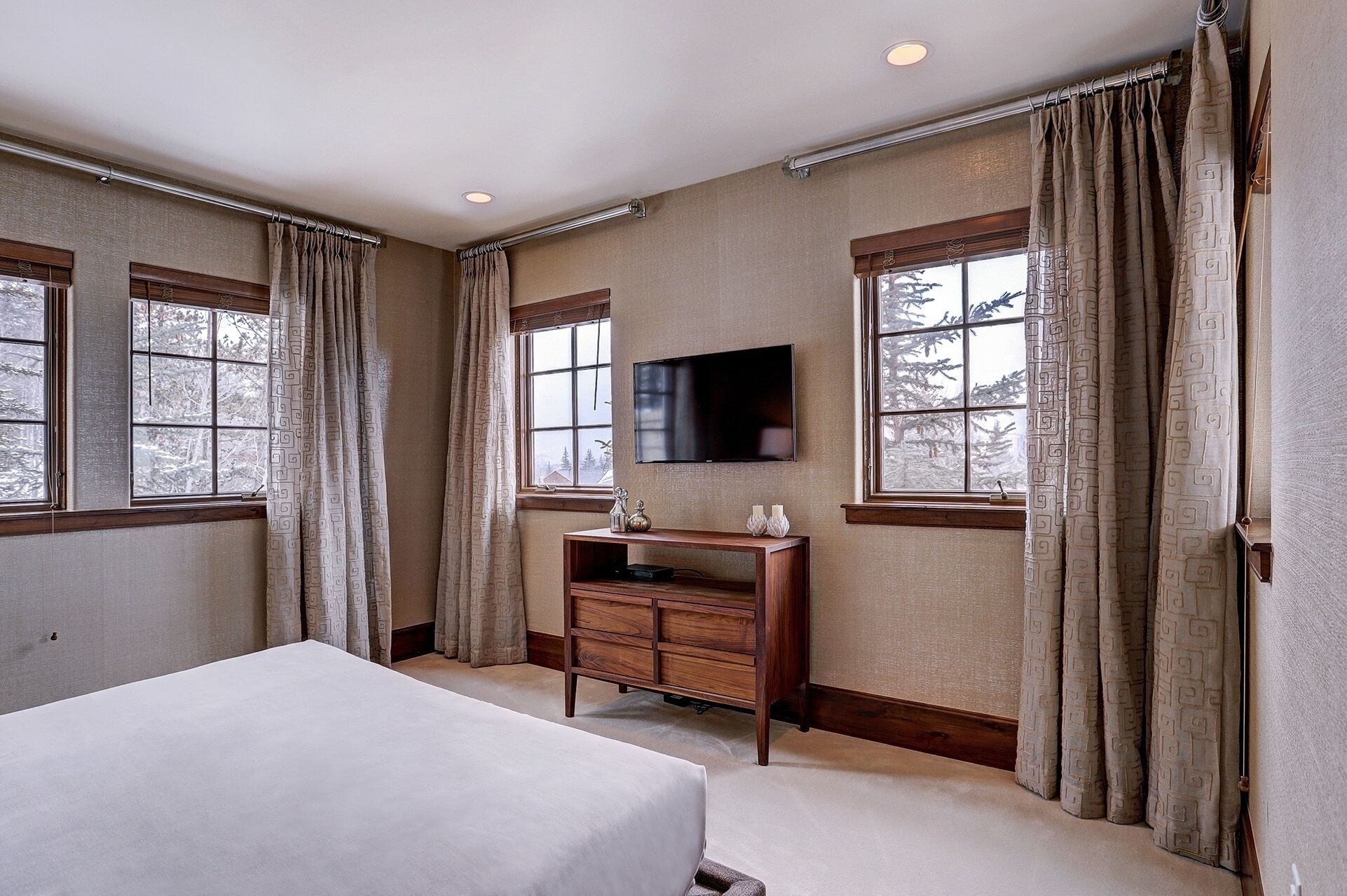 Une chambre à coucher avec un lit, un téléviseur fixé au mur et une commode en bois.