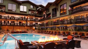 Ein Hotel mit Poolbereich, bequemen Liegestühlen und einem Feuerkorb.