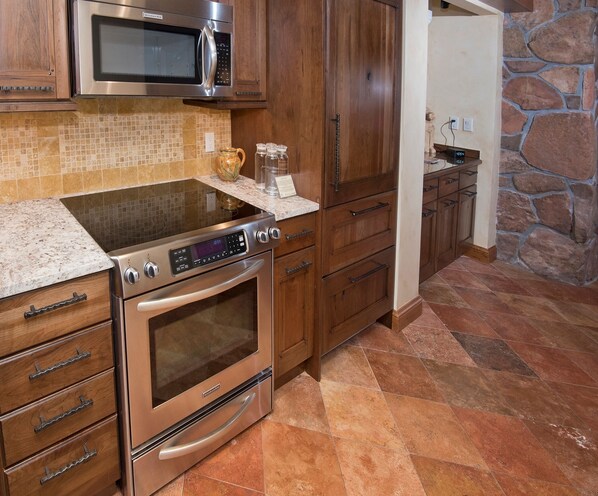 A kitchen with a built-in microwave, oven, and granite countertop.