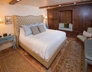 A well-appointed bedroom with a large bed, a wooden bench, and a nightstand with a lamp.