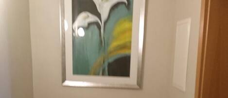 Un escritorio de madera en una habitación con un cuadro enmarcados de flores en la pared.