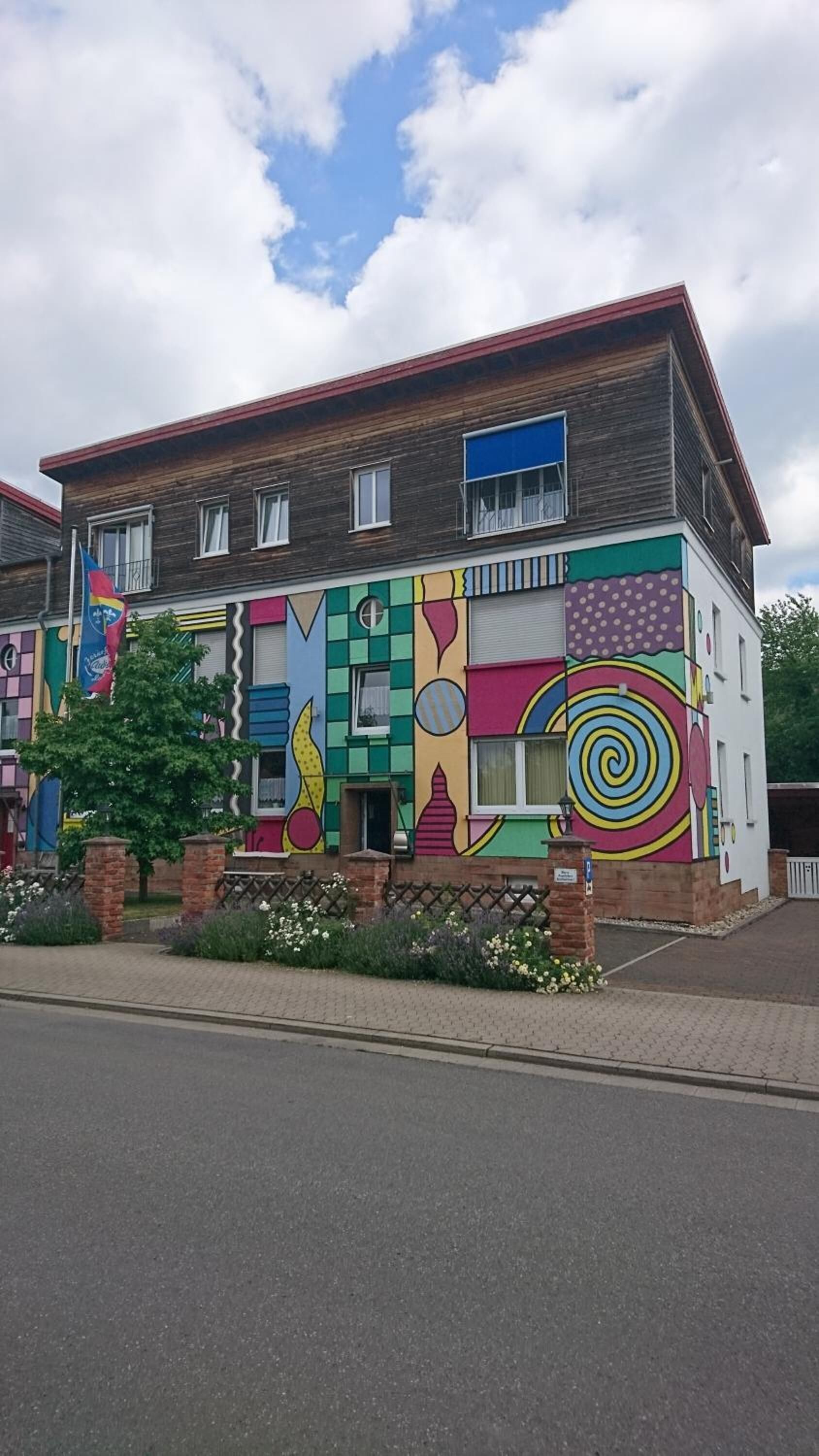 A two-story building with a colorful exterior featuring geometric patterns and a mix of brick and wooden textures.