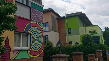 A hotel with a colorful mural on the facade, a reception area, and a landscaped garden with flowers.