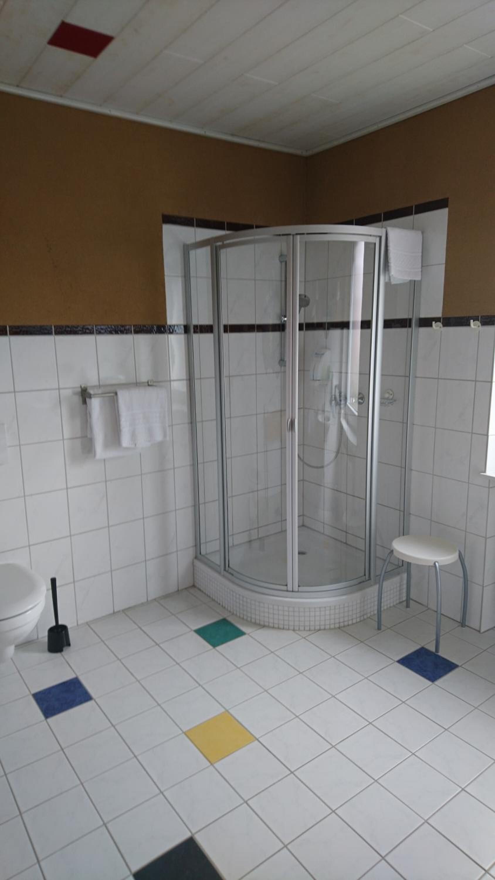 A bathroom with a glass-enclosed shower, a toilet, and a sink.