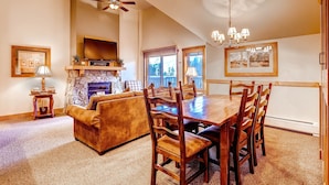 A dining area with a wooden table and chairs, a fireplace, and a television above it. - Red Hawk 2291 (Keystone)