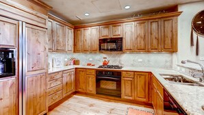 Une cuisine avec des meubles de rangement en bois, un four à micro-ondes, un four traditionnel et un évier.