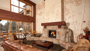 A cozy living room with a stone fireplace, leather sofa, and patterned armchairs. - Springs 8848 (Keystone)