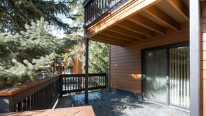 A wooden deck with a black railing, a glass door, and a wooden balcony. - Perfect Mountain Retreat/3br -fireplace, Kids Ski Free 3 Bedroom Condo by RedAwning (Keystone)