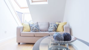 A modern living room with a grey sofa, a glass coffee table, and a view of a balcony.