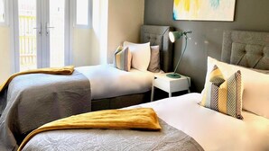A hotel room with two beds, a nightstand, a lamp, and a large abstract painting on the wall.
