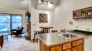 Een moderne keuken met een groot eiland, een eethoek met een ronde tafel en uitzicht op de stad door grote ramen.