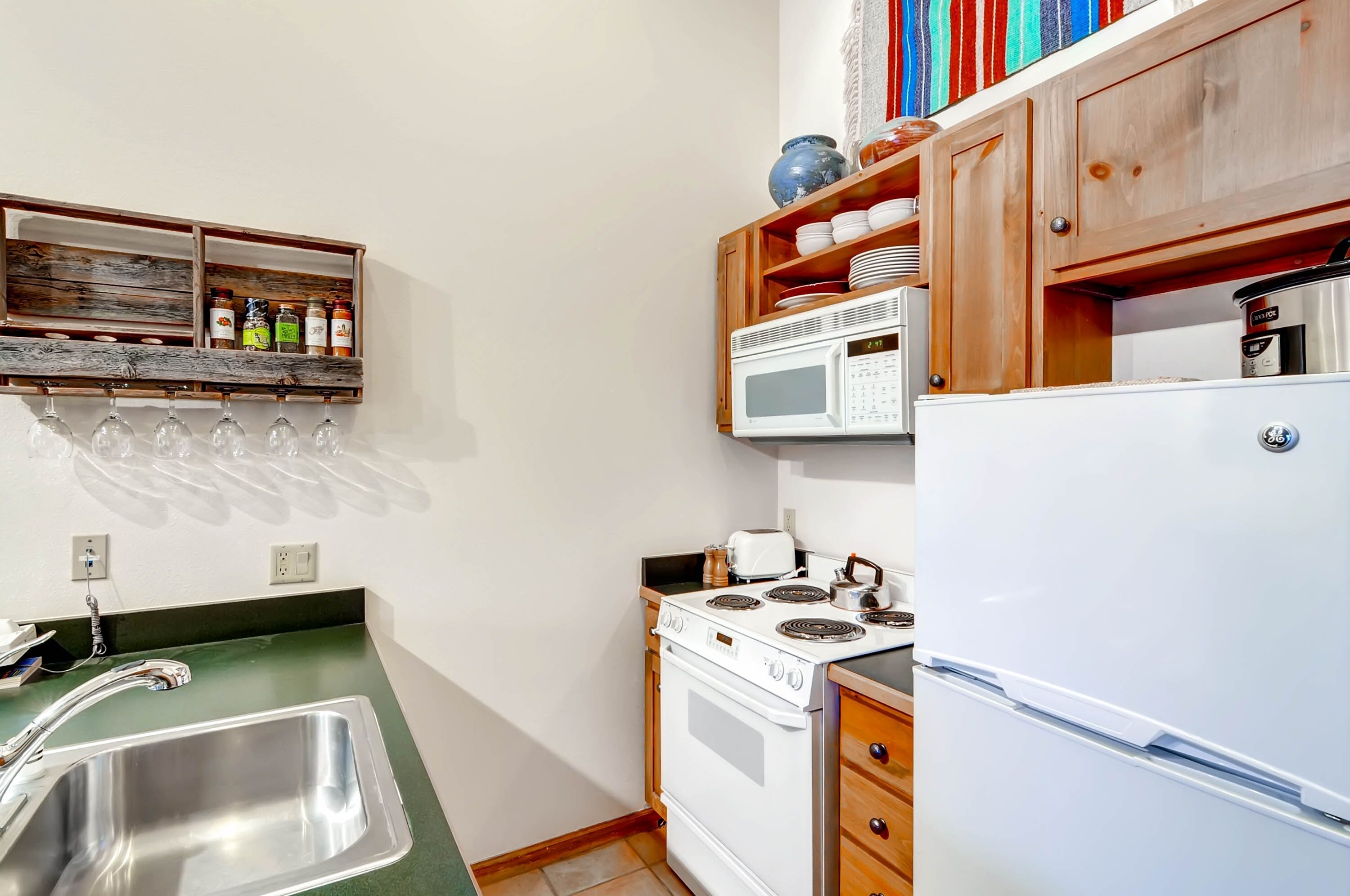 A compact kitchen with a sink, stove, microwave, and refrigerator.