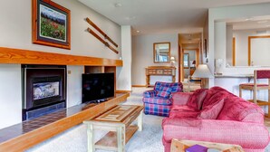 Ein Wohnzimmer mit Kamin, Fernseher und einem roten Sofa.