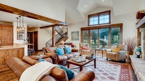 A spacious living area with leather sofas, a coffee table, and a large window offering a view of the outdoors.