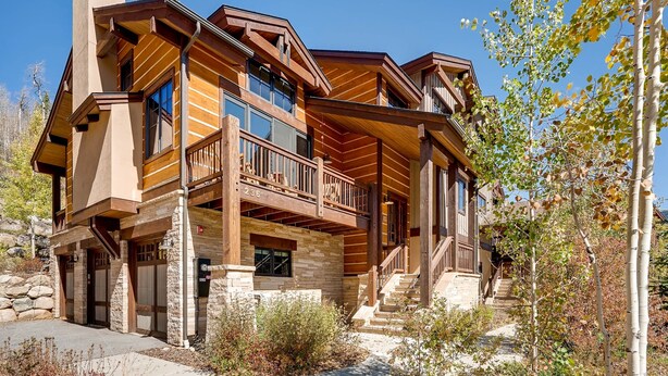 A multi-story log cabin with a stone foundation, wooden balconies, and a stone staircase.