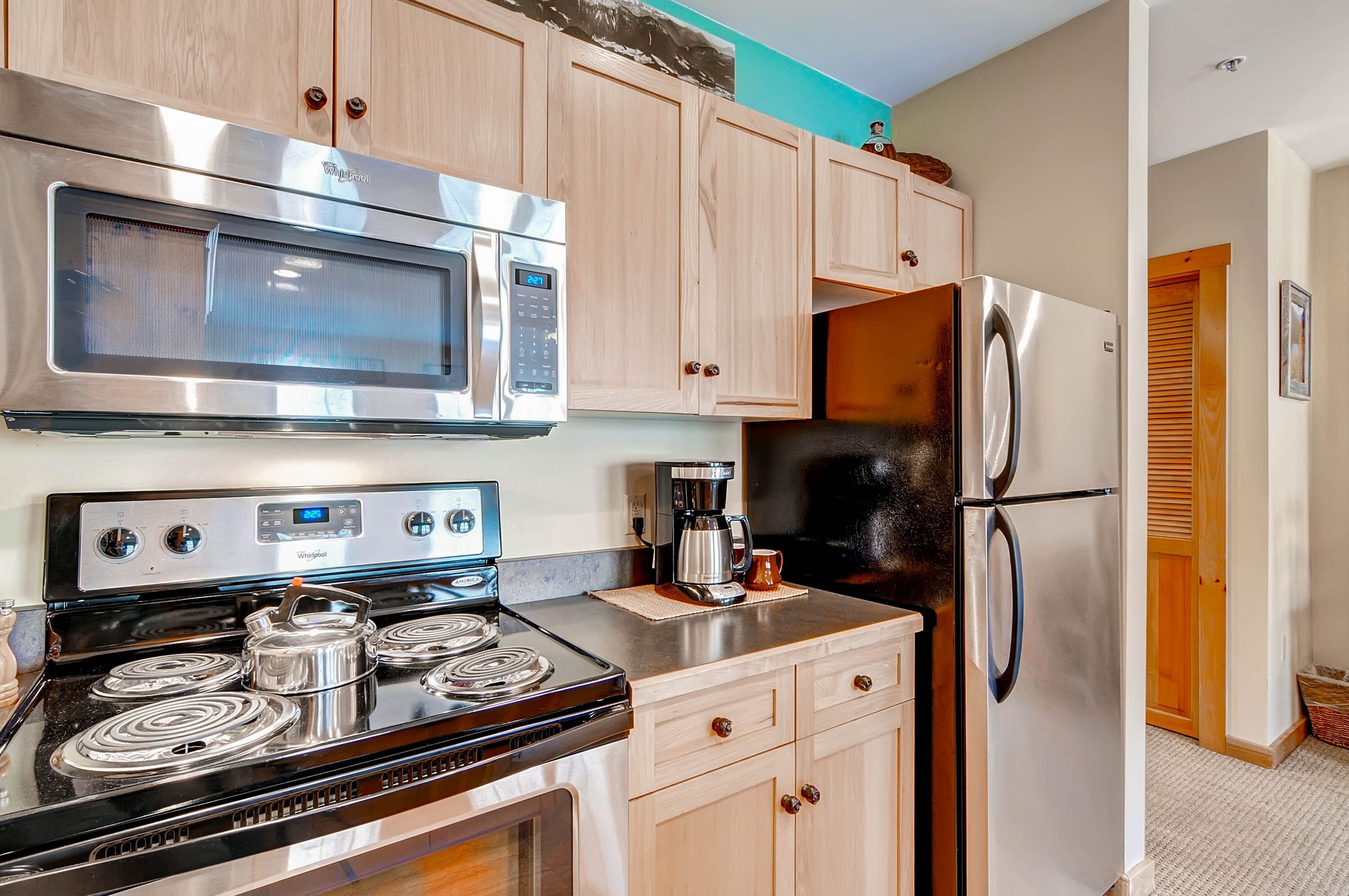 A kitchen with stainless steel appliances, wooden cabinets, and a coffee maker.