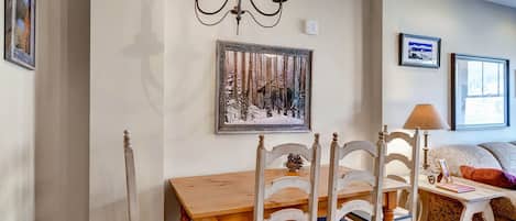 A dining area with a wooden table and chairs, a chandelier, and framed pictures on the walls.