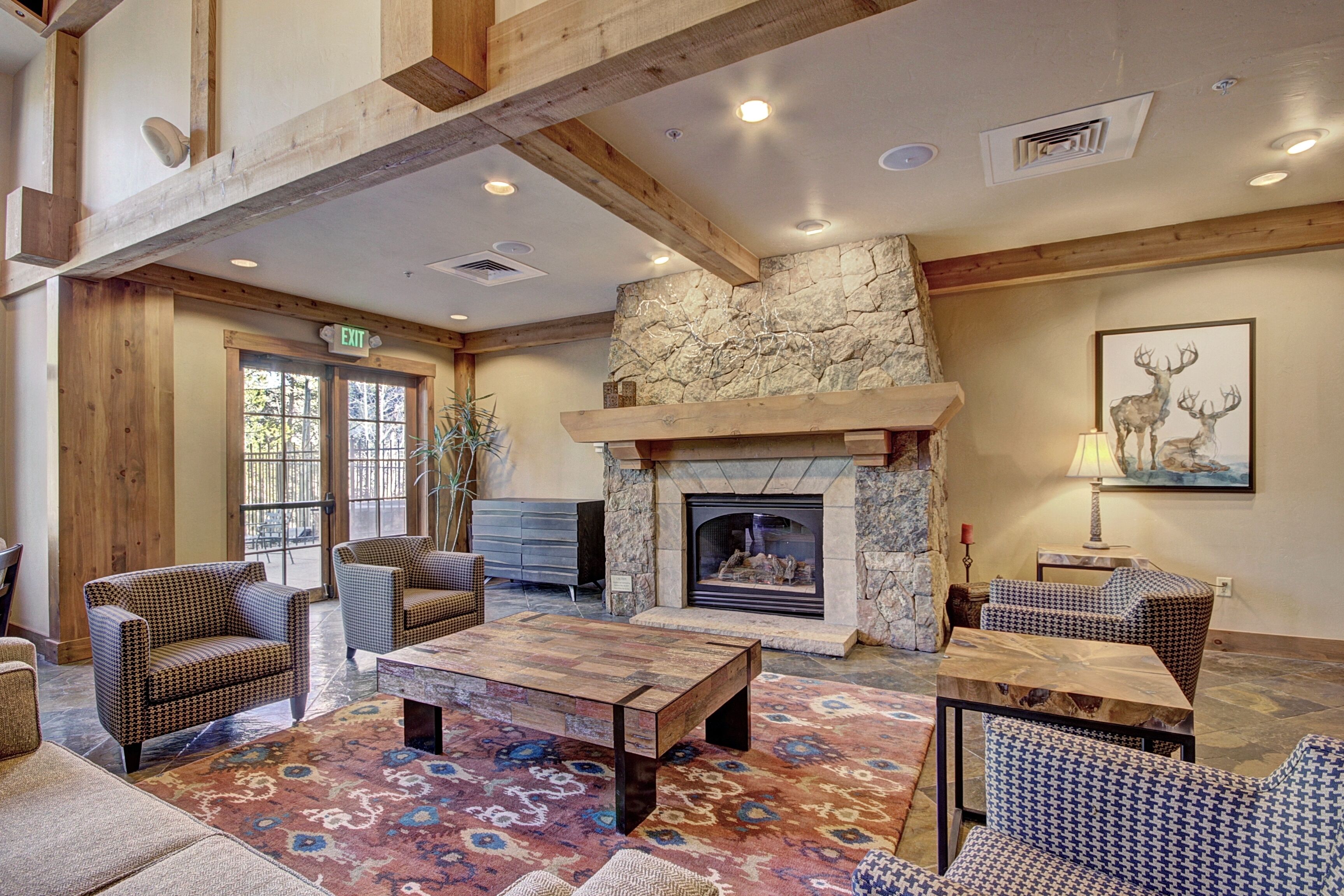 A spacious lobby with a stone fireplace, wooden beams, and patterned rugs.