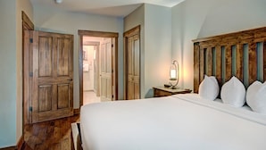 A bedroom with a large bed, wooden wardrobe, and a bedside table with a lamp. - Luxe 2br 2ba - Rocky Mountain Views + Walk To Mainstreet 2 Bedroom Apts by RedAwning (Breckenridge)